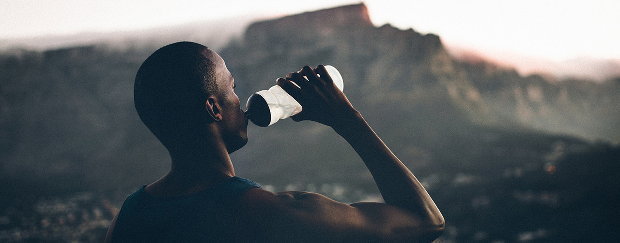 African descent athlete drinking water after a fitness achievement
