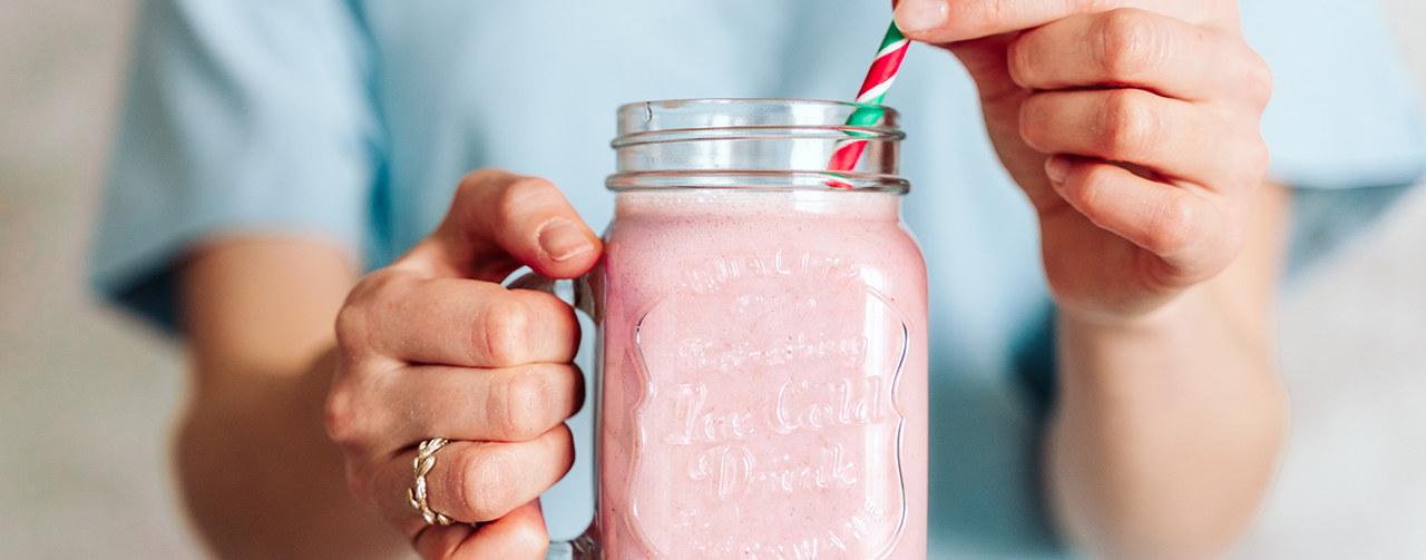 Woman holding a jar with pink milkshake