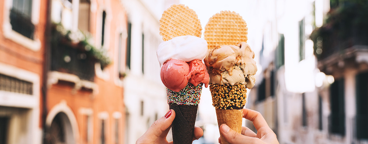 Hands holding trendy ice creams with biscuit, sprinkles