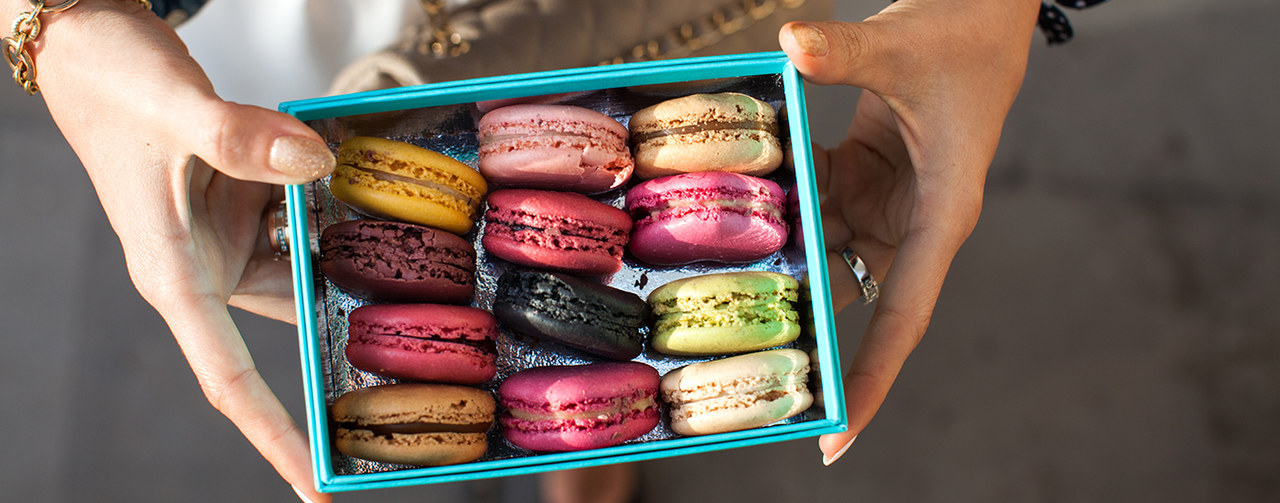 Top view of a woman holding box with colourful macaroons