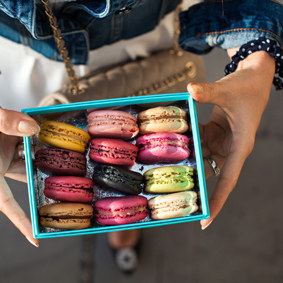 Top view of a woman holding box with colourful macaroons