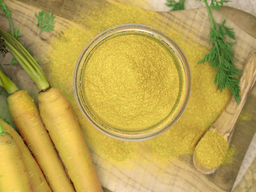 Top view of yellow carrot powder with raw carrots on table