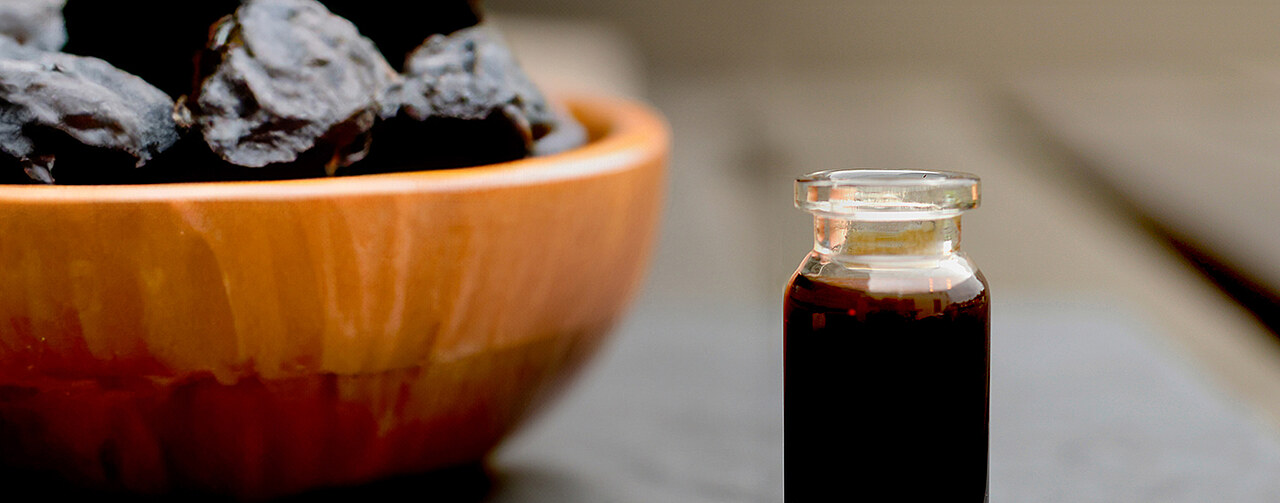 prune juice concentrate in a glass jar and prunes on a table