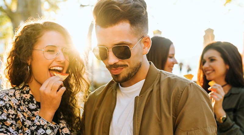 Happy couple sharing cocktail and dips at an outside party