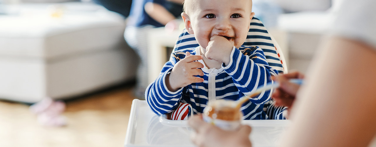 Mother feeding her baby with savoury meal or dessert