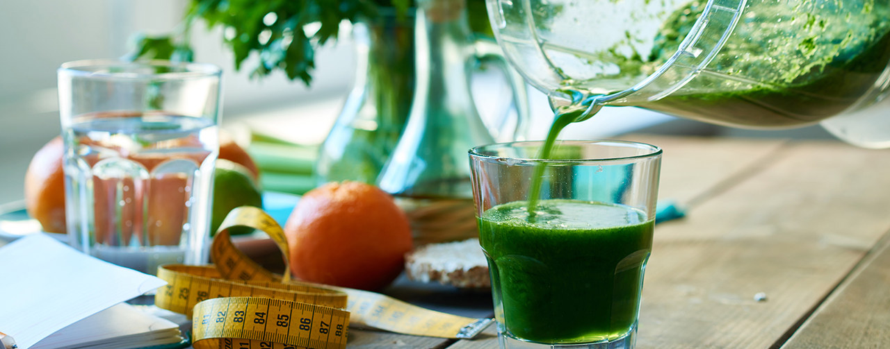 Pouring green detox smoothie in a glass