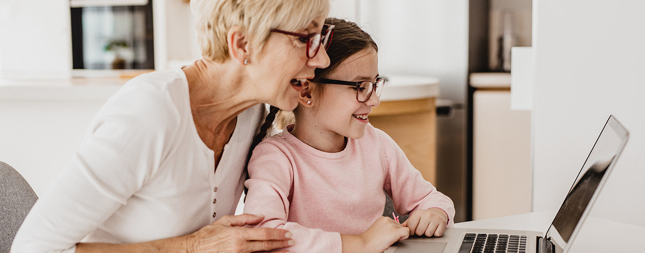 Granddaughter and senior woman using laptop