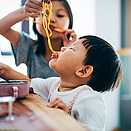 Asian little girls eating noodles at home