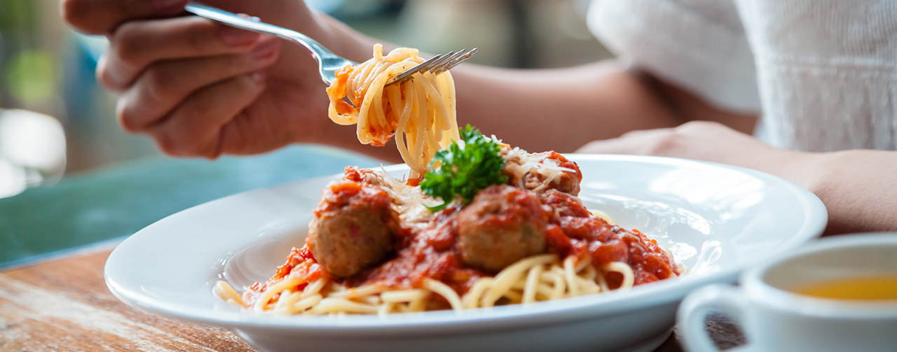 Woman eating spaghetti with meat balls and tomato sauce