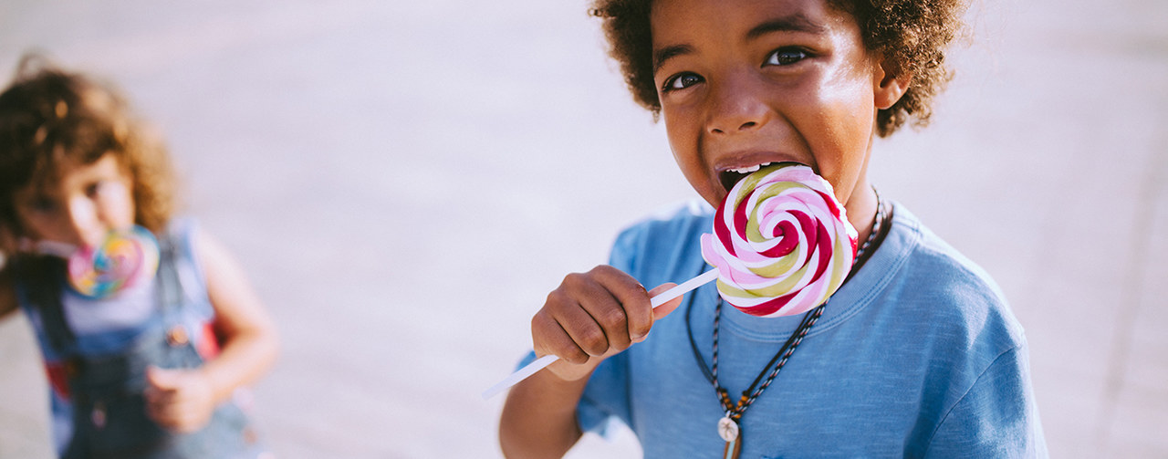 Children eating colourful lollipops outdoors