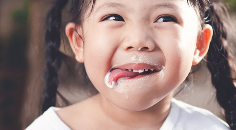 Asian child licking his lips covered in milk