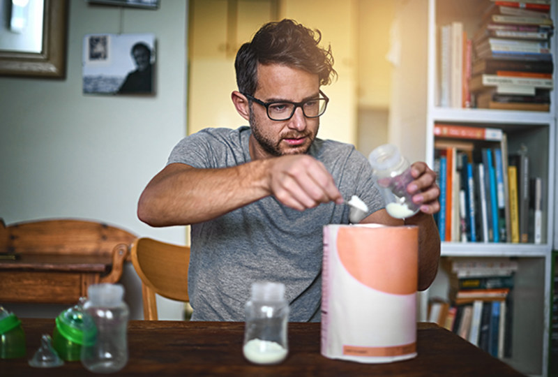 Cropped shot of a father preparing a bottle for his baby at home