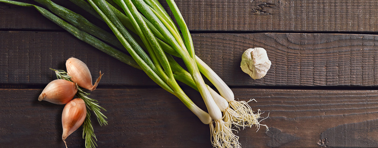 Top view of fresh leek, shallot and garlic on wooden table