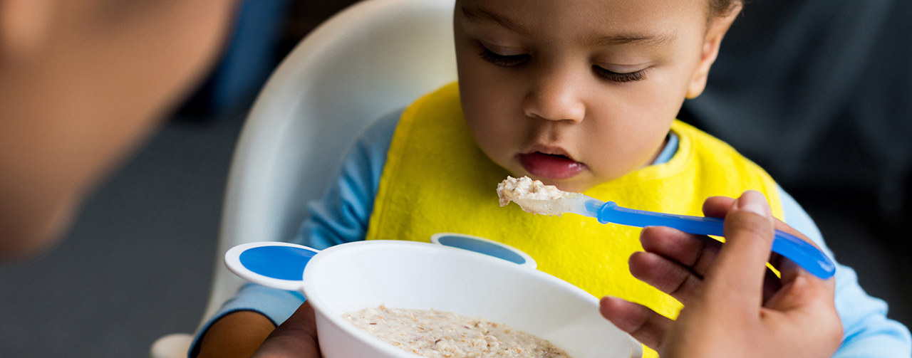 Little boy eating infant cereals porridge