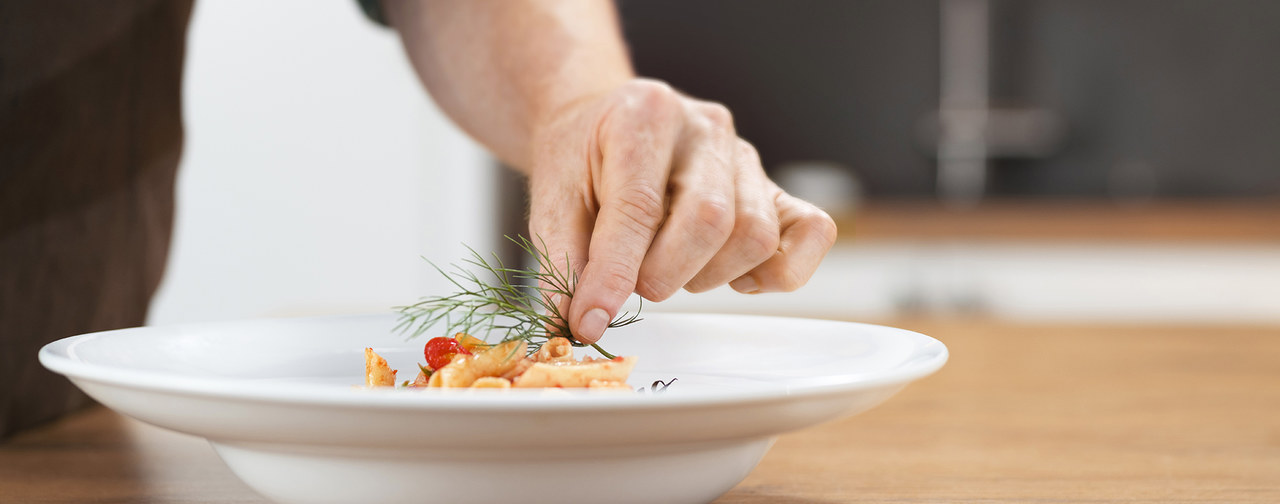 Chef adding herbs on his ready meal