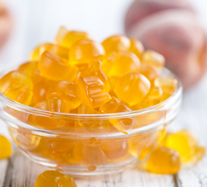 Close up of orange gummies with peach on table