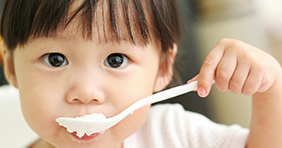 Young girl eating with spoon