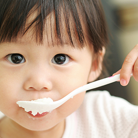 Young girl eating with spoon