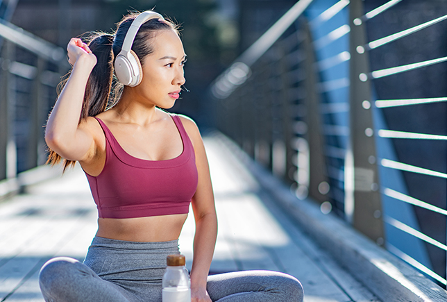 Asian sportive woman relaxing, listening music 