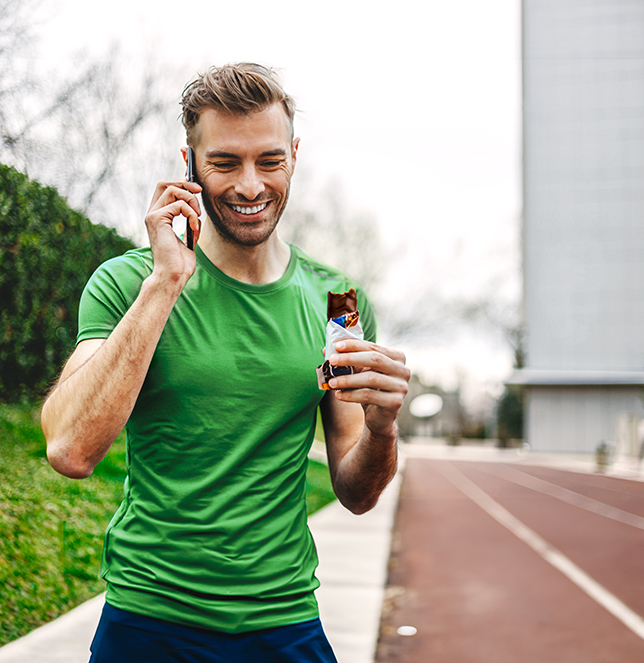 Sporty man on the phone, eating a snack