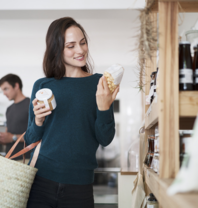 smiling woman looking at the label of a product in a supermarket