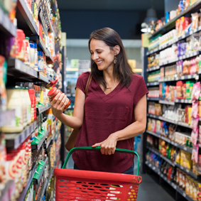 A smiling woman at supermarket looking label's product