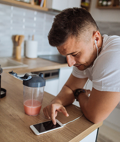 Young man using food and drink app on smartphone in kitchen