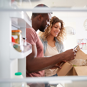 View Looking Out From Inside Of Refrigerator As Couple Unpack Online Personalized Home Food Delivery