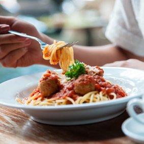 Woman eating spaghetti with meat balls and tomato sauce