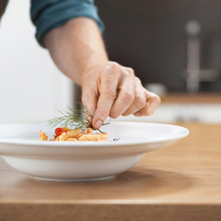 Chef adding herbs on his ready meal