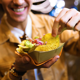 Young man eating nachos in the street