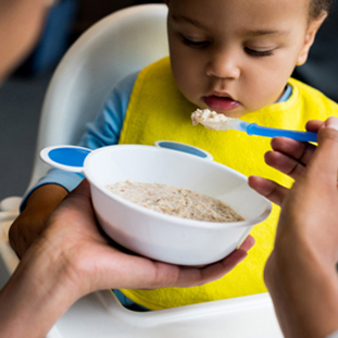 Little boy eating infant cereals porridge