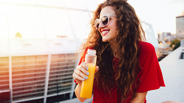 Happy woman drinking fresh juice outdoors