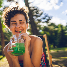 Smiling woman drinking green instant drink in a jar