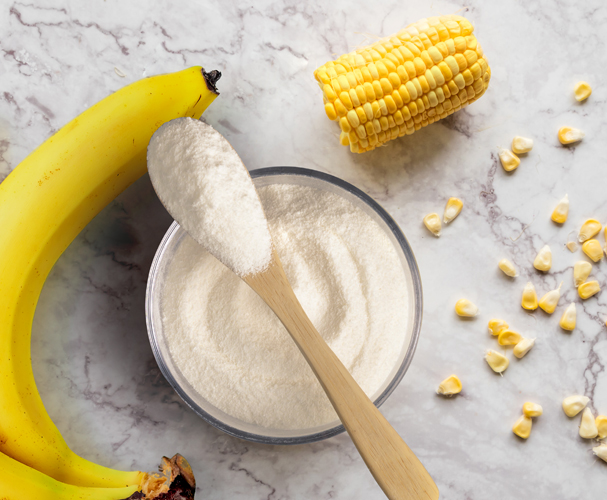 Top view of banana and sweet corn raw ingredients and powder on marble table