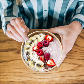 Crop woman close up eating oat and fruits bowl for breakfast