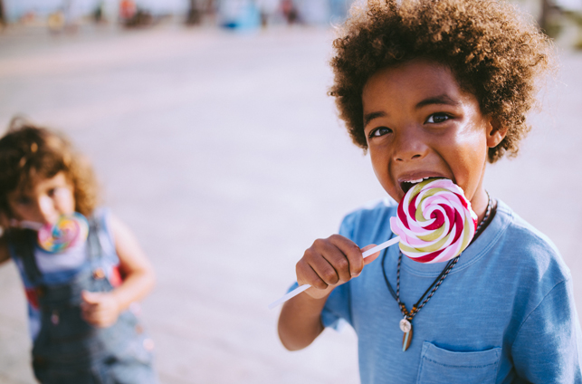 Children eating colourful lollipops outdoors