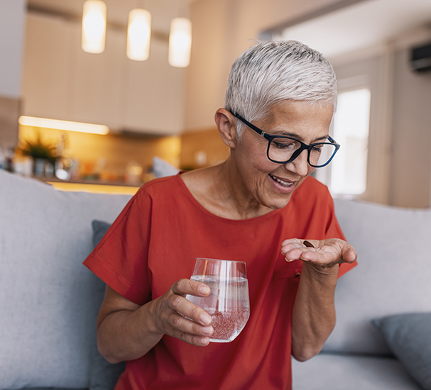 Mature woman taking pill on her sofa