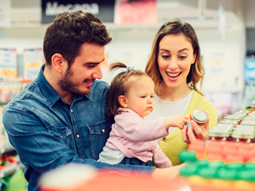 Parents buying baby food with their child in supermarket