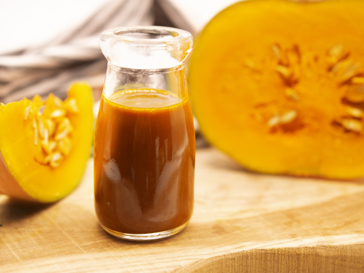 Pumpkin juice concentrate with raw pumpkin on table