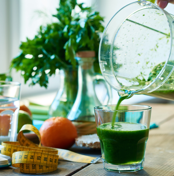 Pouring green detox smoothie in a glass
