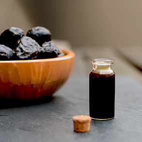 prune juice concentrate in a glass jar and prunes on a table