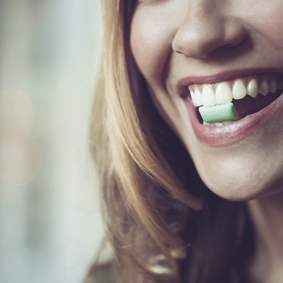 Happy woman holding chewing gum with her teeth