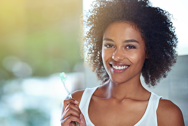 smiling woamn holding toothbrush for oral health