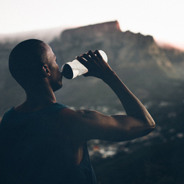 African descent athlete drinking water after a fitness achievement