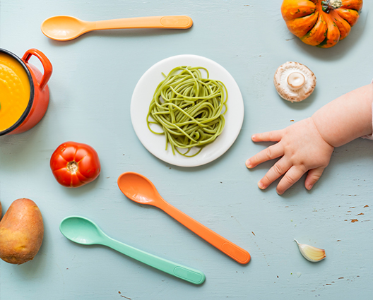 fresh tomato, garlic, pumpkin, soup and noodles with baby arms on wooden table